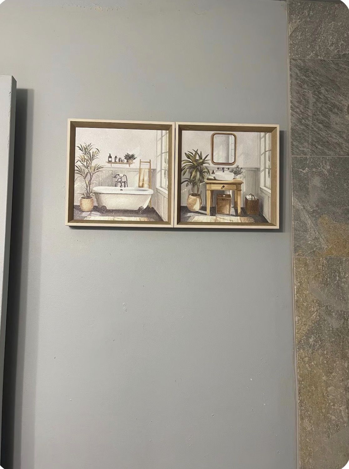 A wall with two framed illustrations of a bathroom.