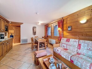 Een gezellig chaletinterieur met een eethoek, houten wanden en een bank met een patroon gestoffeerd.