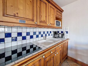 A kitchen with wooden cabinets, a microwave, a coffee maker, and a tiled backsplash. - Spacious apartment for 6 with pool access (Les Menuires)