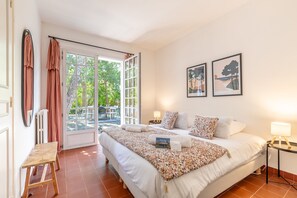 Habitació d'hotel amb un llit, una taula de treball, una cadira, una taula, una làmpada i dues fotografies emmarcades a la paret.
