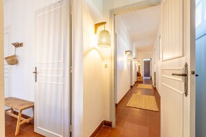 A hallway with white doors, a wooden bench, and a woven basket on the wall. - Villa Subera - à 2 min du lac d'Hossegor (Hossegor)