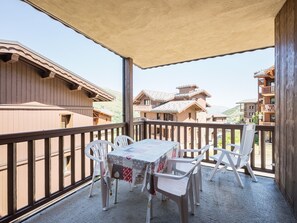 Ein Balkon mit Tisch und Stühlen mit Blick auf eine gebirgige Landschaft und Holzhäuser.