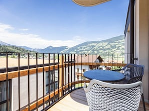 Varanda com vista para montanhas, uma mesa e uma cadeira.