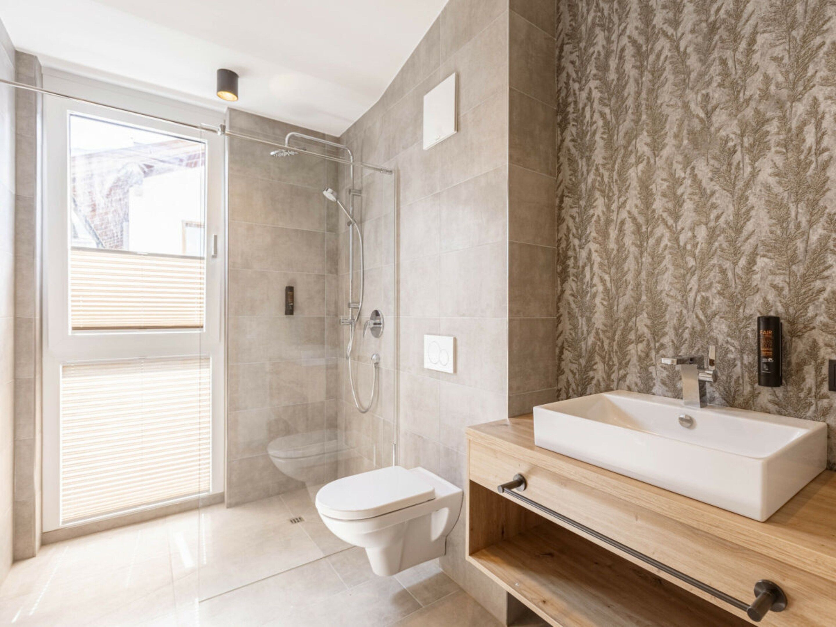 A modern bathroom with a glass-enclosed shower, a toilet, and a wooden vanity with a white sink.
