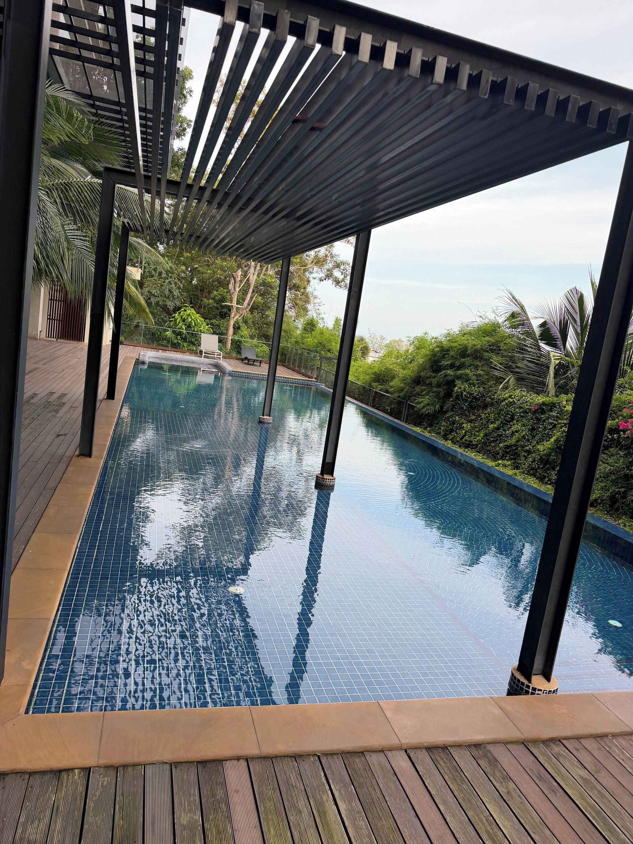 Una piscina infinita con terraza de madera y vista al océano.