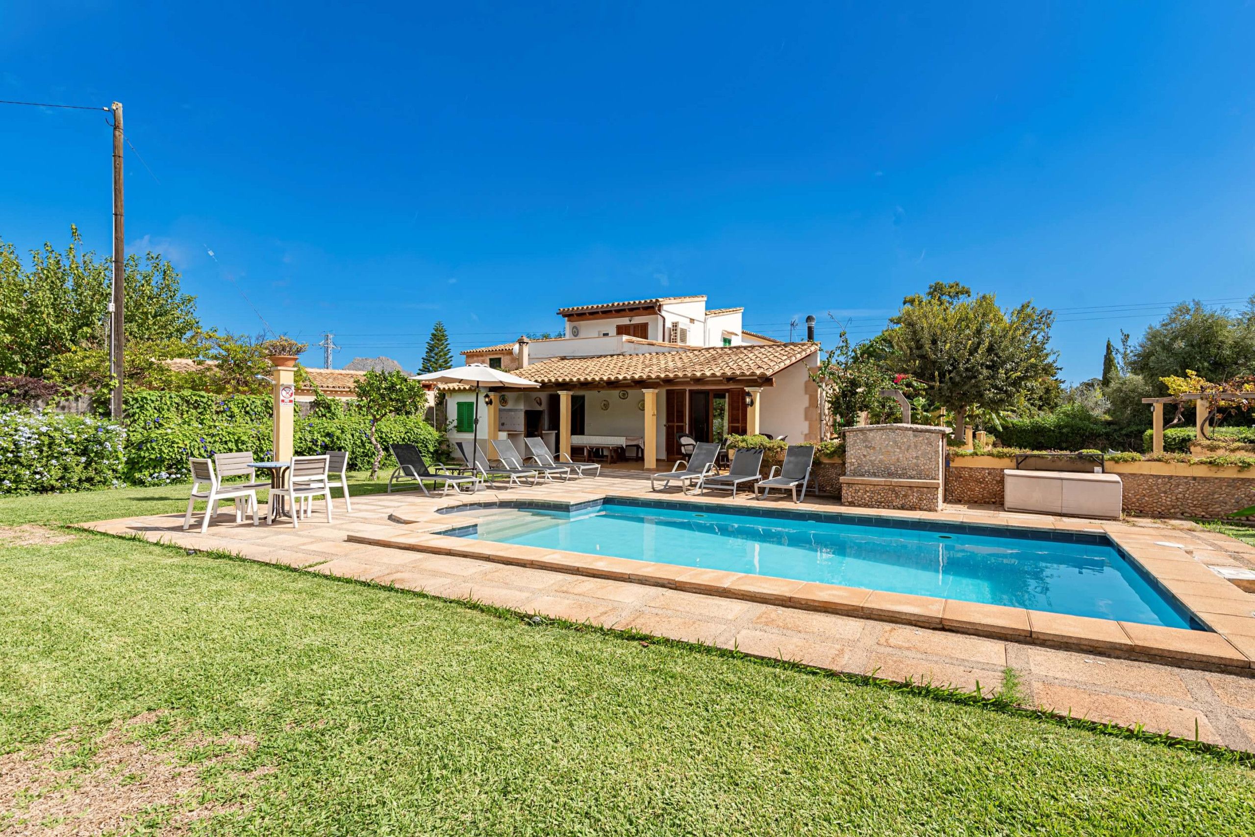 A two-story house with a swimming pool, outdoor seating, and a well-maintained garden.