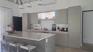 A modern kitchen with a central island, bar stools, and a window above the sink. - Private 2 Bed, 2 Bath Tropical Bungalow in upscale Christophe Harbour w Tennis (Saint George Basseterre Parish)