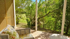 An outdoor seating area with wicker furniture and a view of a lush garden. - Private 2 Bed, 2 Bath Tropical Bungalow in upscale Christophe Harbour w Tennis (Saint George Basseterre Parish)