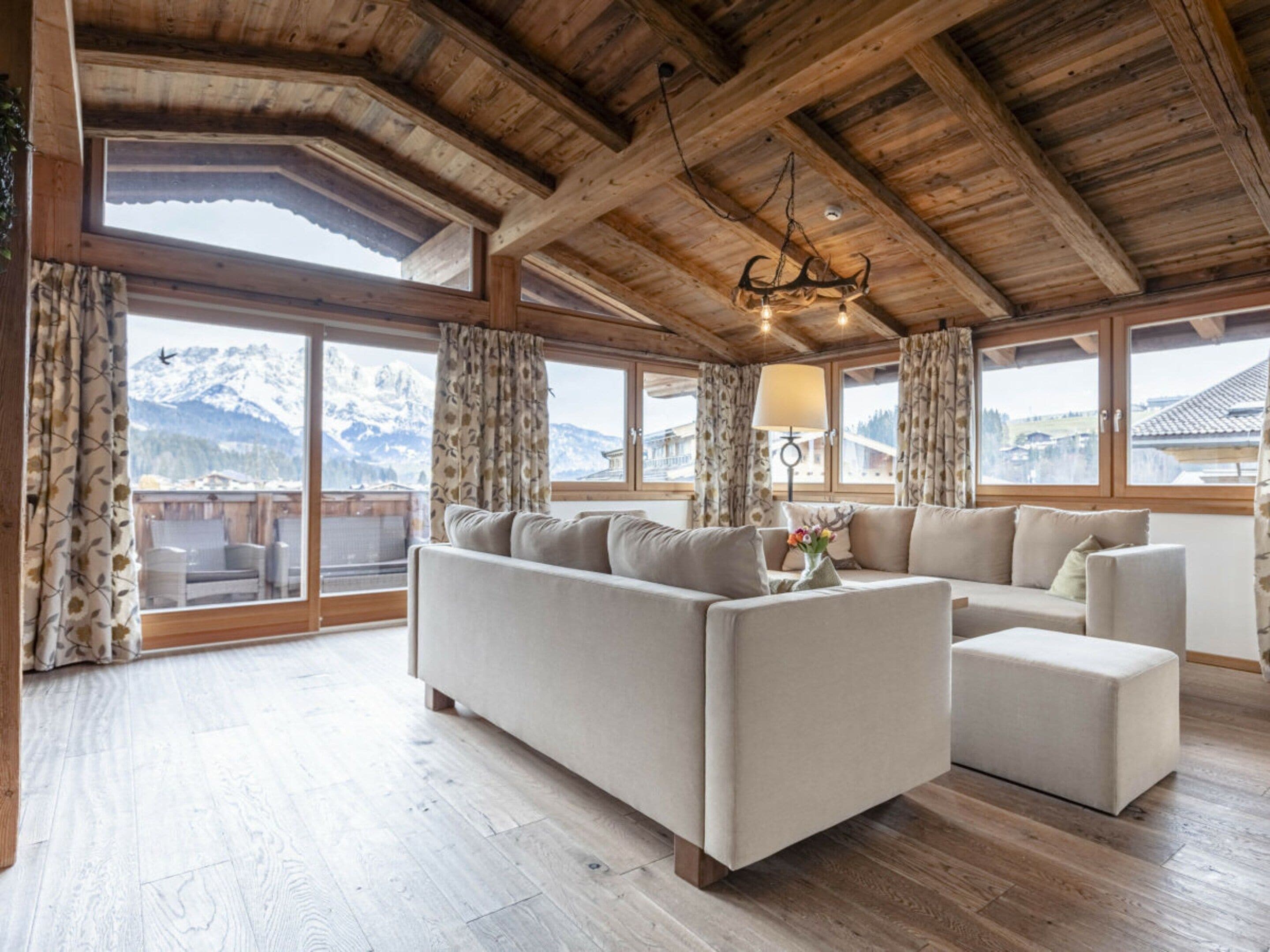 A spacious living room with a large sofa, a coffee table, and a chandelier.