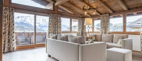 A spacious living room with a large sofa, a coffee table, and a chandelier.