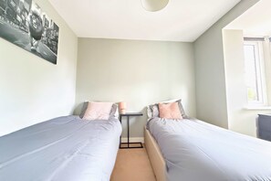 Ein Schlafzimmer mit zwei Einzelbetten, einem kleinen Tisch und einem Fenster.