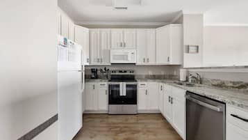 A kitchen with white cabinets, a stainless steel dishwasher, a microwave, and an oven.