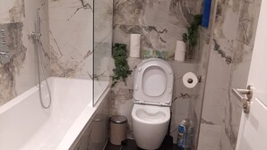 Een badkamer met een bad, toilet en douche.