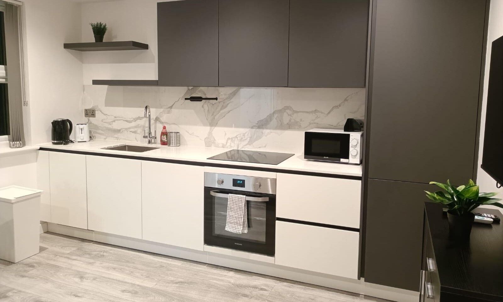 A modern kitchen with a built-in oven, microwave, and a coffee maker on the countertop.