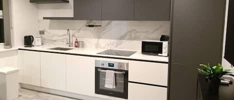 A modern kitchen with a built-in oven, microwave, and a coffee maker on the countertop.