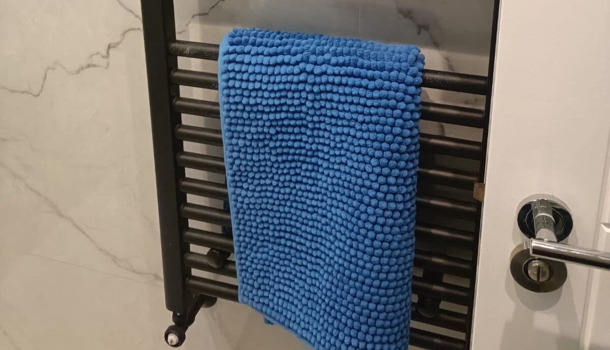 A bathroom with a towel rack holding a blue towel.