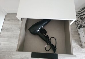A drawer with a hair dryer inside.