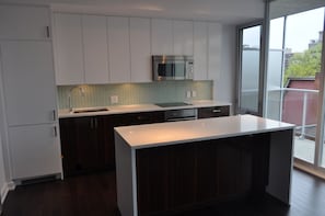 Een moderne keuken met witte kasten, een roestvrijstalen magnetron en een groot eiland.