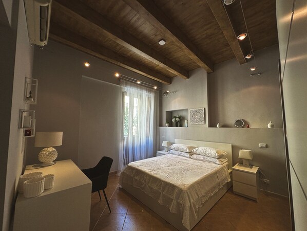 A bedroom with a bed, bedside tables, a desk, and a chair.