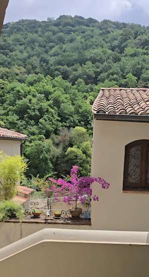 A building with a tiled roof and a balcony with potted plants and flowers. - Home Don Luigi Studio Apartment in Historic Building (Lamezia Terme)
