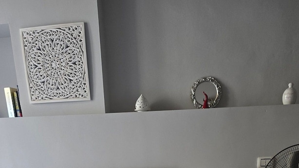 Een slaapkamer met een bed, nachtkastje, lamp en een ventilator.