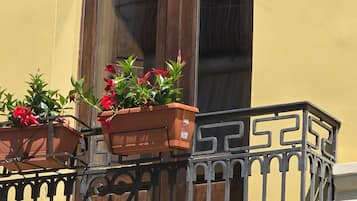 Un balcón con barandilla de hierro forjado y plantas en macetas.