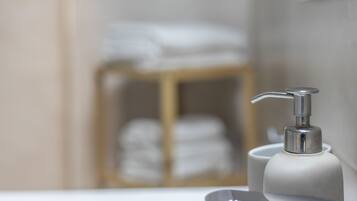 Un baño con un lavamanos blanco, un grifo plateado y un toallero de madera al fondo.