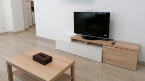 Un saló modern amb televisió de pantalla plana, mobles de fusta i una taula petita amb un objecte de maó.