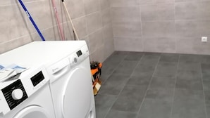 Zona de bugaderia amb rentadora, un esfregador i una escombra.