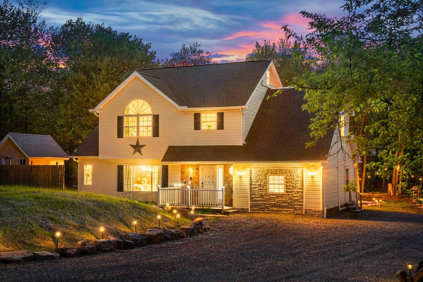A two-story house with a porch, a stone wall, and a star decoration.