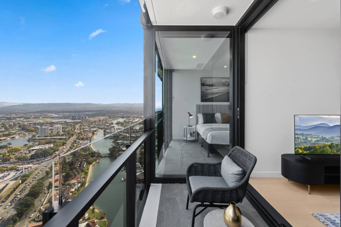 A modern balcony with a glass railing overlooking a cityscape and river.