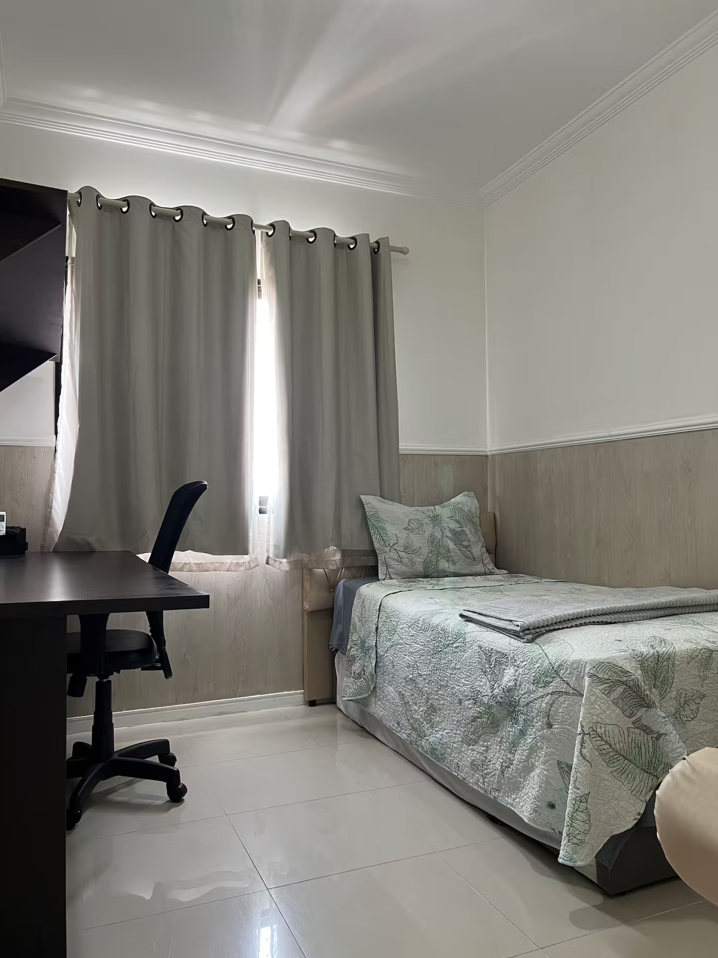A bedroom with a bed, a desk, and a chair.