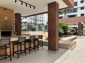 An outdoor bar area with a brick wall, seating, and a TV screen. - 2802 Parc · Luxury and comfortable 3-bedroom apartment with garage (Belém)