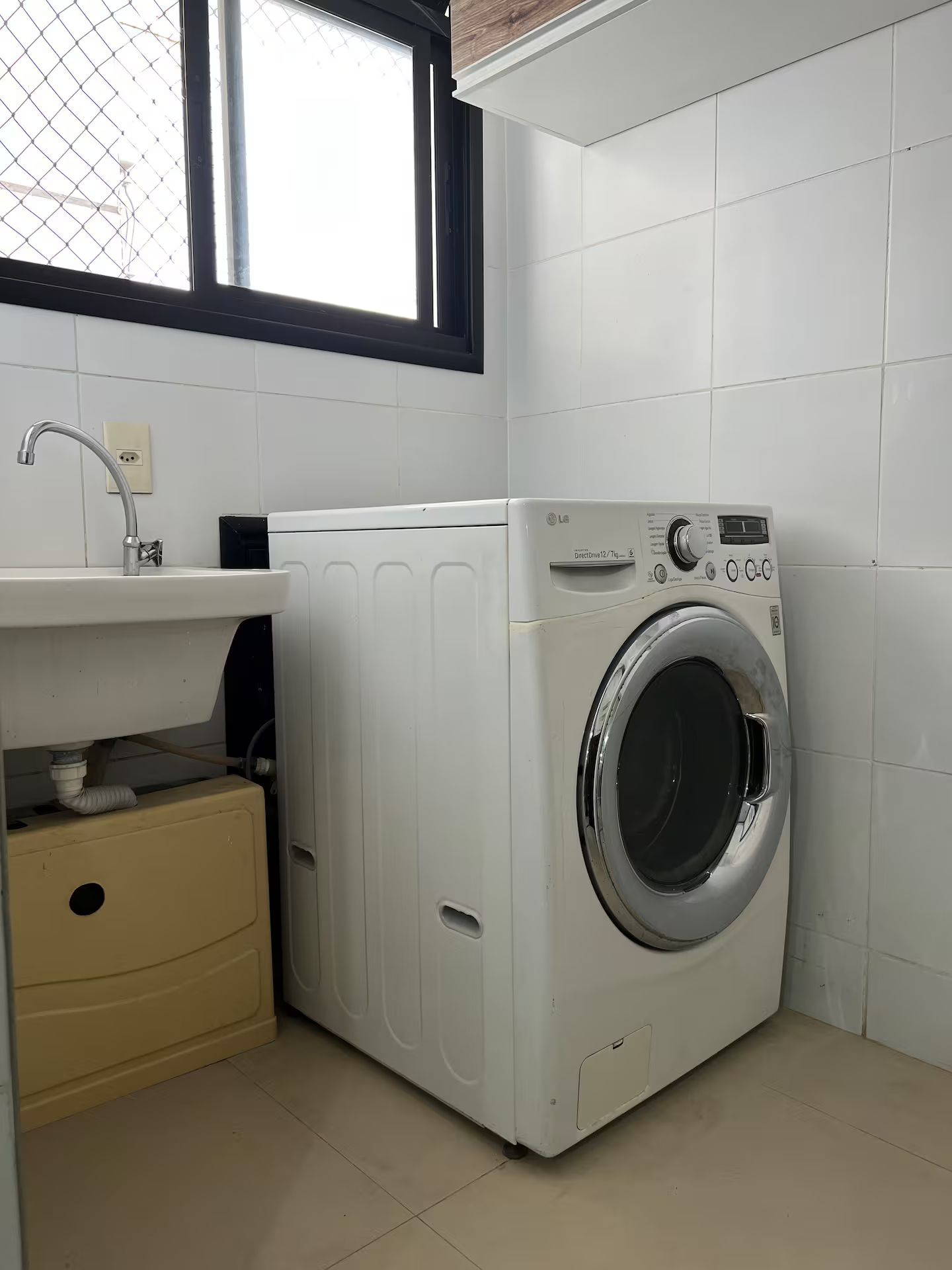 A compact laundry room with a front-loading washing machine, a sink, and a small cabinet.