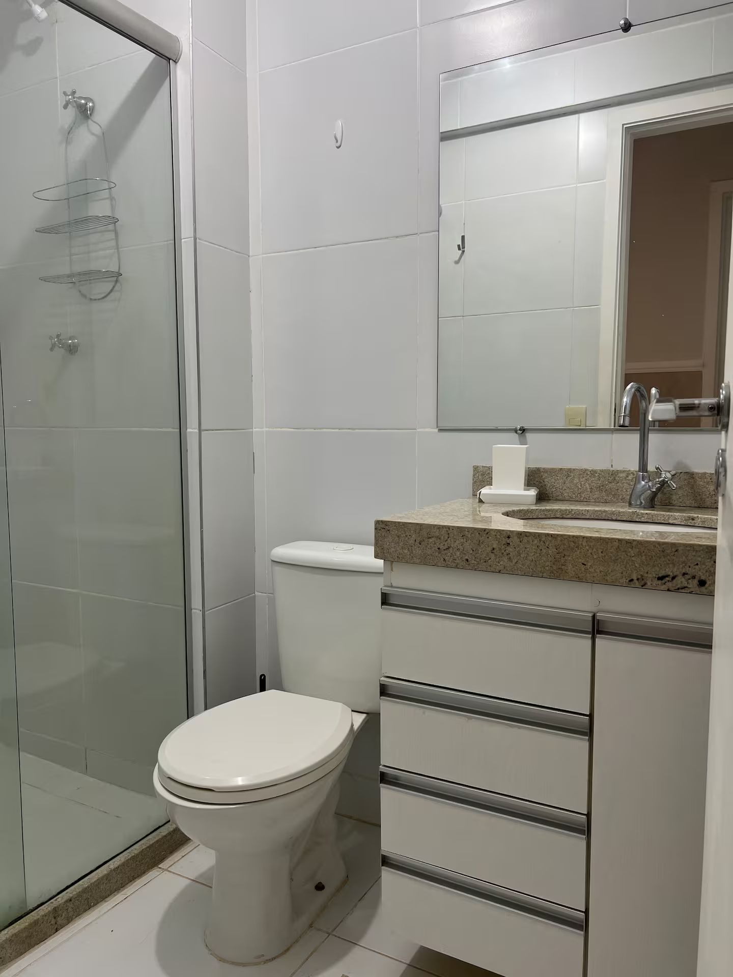 A bathroom with a toilet, a sink, and a shower area.