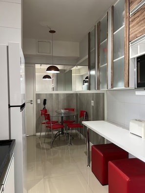 A modern kitchen with a dining area, white cabinetry, and red chairs. - 2802 Parc · Luxury and comfortable 3-bedroom apartment with garage (Belém)