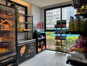 Ein Geschäftinnenraum mit Regalen voller Snacks, einer Kühlvitrine und einem Fenster mit Blick auf Gebäude.