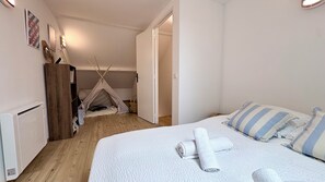 A bedroom with a bed, a white quilt, and a striped pillow. There is a tent in the corner and a radiator on the wall. - Ilha Grande - Country House in the Somme Bay (Ponthoile)