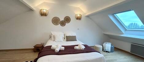 A bedroom with a large bed, a skylight, and wall-mounted lighting fixtures.