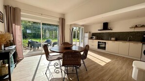 Eine moderne Küche mit Essbereich, großen Fenstern und Blick ins Freie.