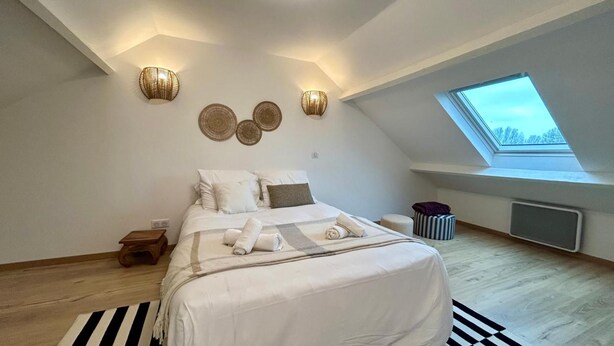 Ein Schlafzimmer mit einem Bett, einem Oberlicht und Wandleuchten.