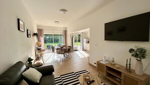Ein modernes Wohnzimmer mit einer schwarzen Ledersofa, einem Holztisch und einem an der Wand befestigten Flachbildfernseher.