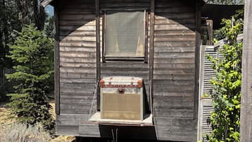 Een klein houten huisje met een horrekenraam en een oude koffer aan de gevel.