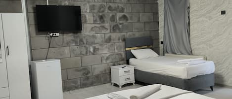 Una habitación de hotel con cama, mesita de noche, televisor y armario.
