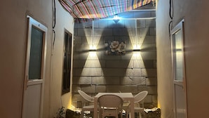 A patio area with a table and chairs, a patterned ceiling, and wall-mounted lights. - SUR-U ALA HOTEL (Diyarbakır)
