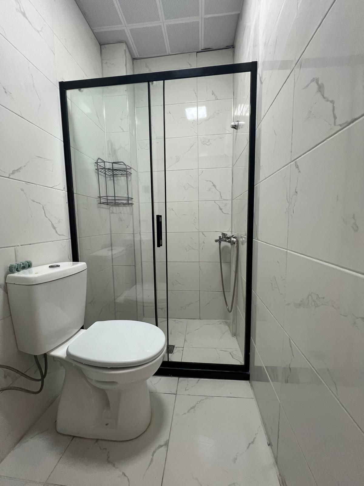 A bathroom with a toilet, a shower enclosure, and tiled walls.