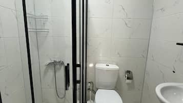 A bathroom with a glass-enclosed shower, a toilet, and a sink.