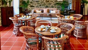 Un comedor con mobiliario de mimbre y un fondo de pared de piedra.
