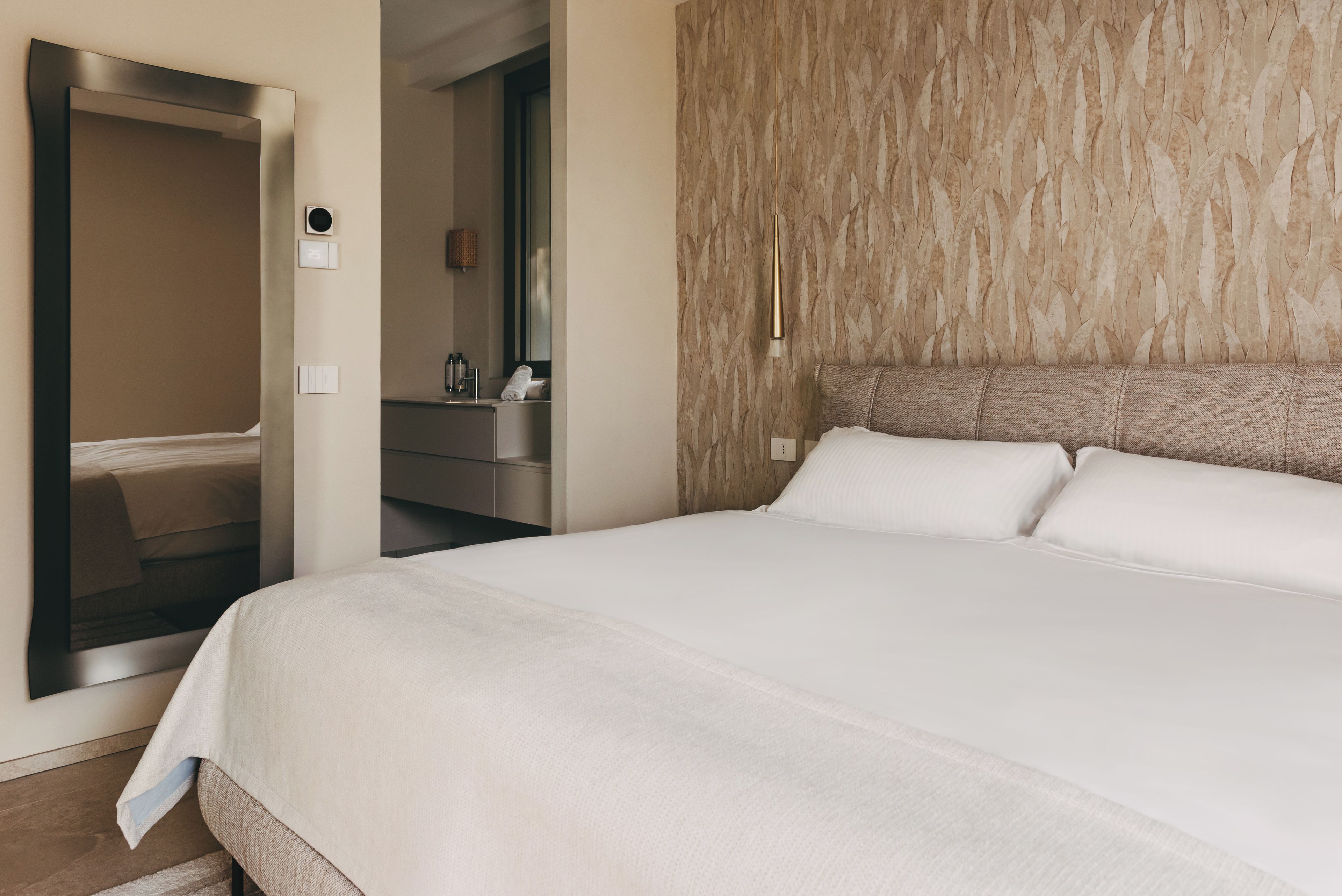 A hotel room with a bed, a bathroom, and a mirror.