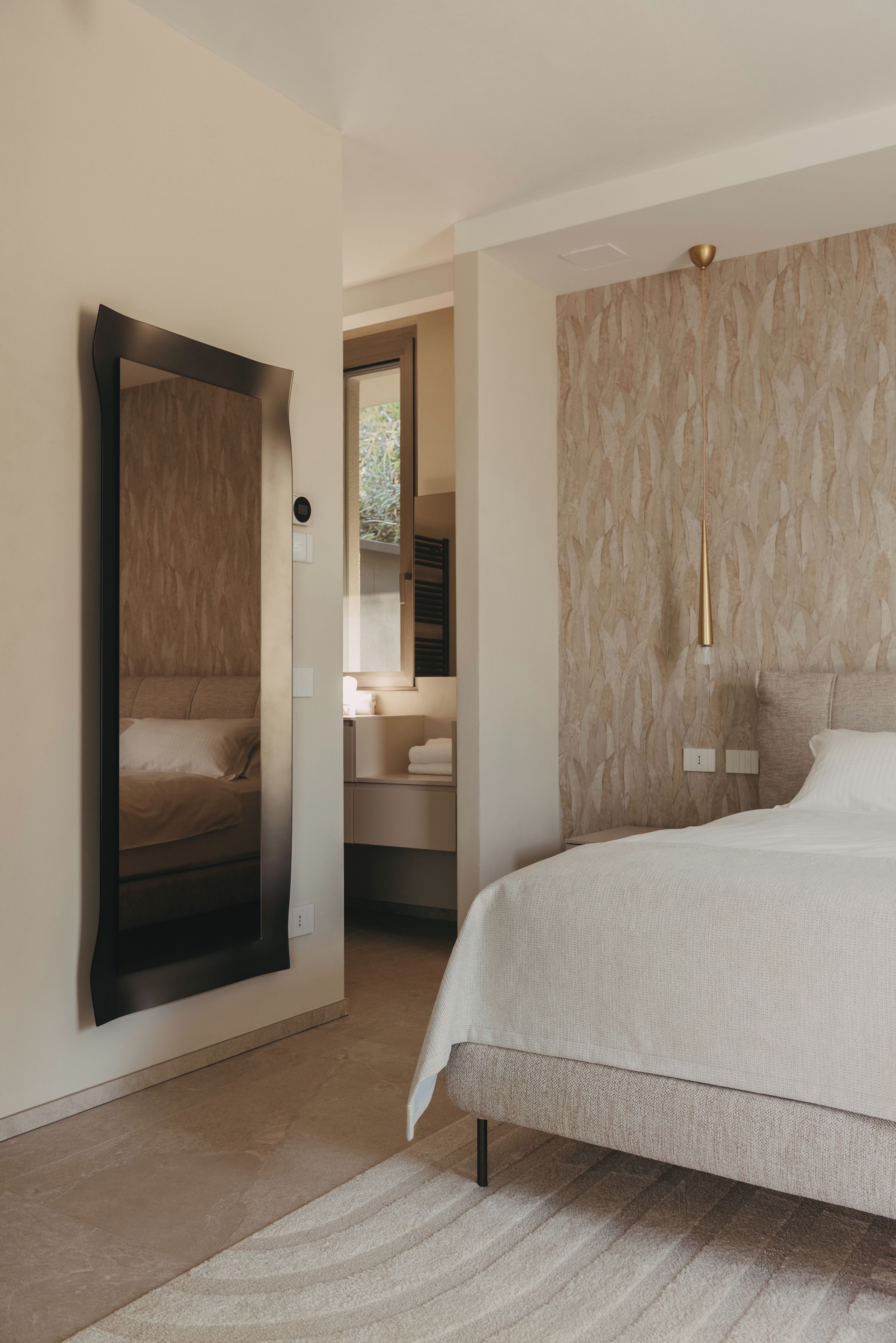 Une chambre à coucher moderne avec un grand lit, une armoire et un miroir.